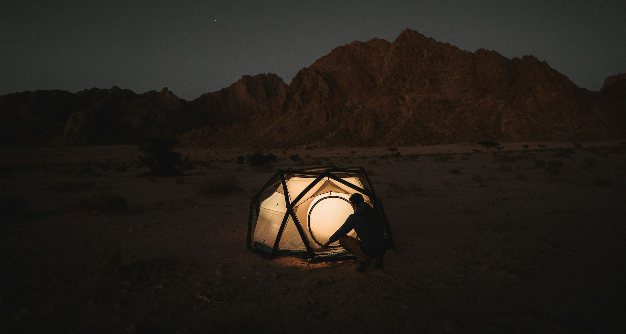 a person sitting inside of a tent in the desert