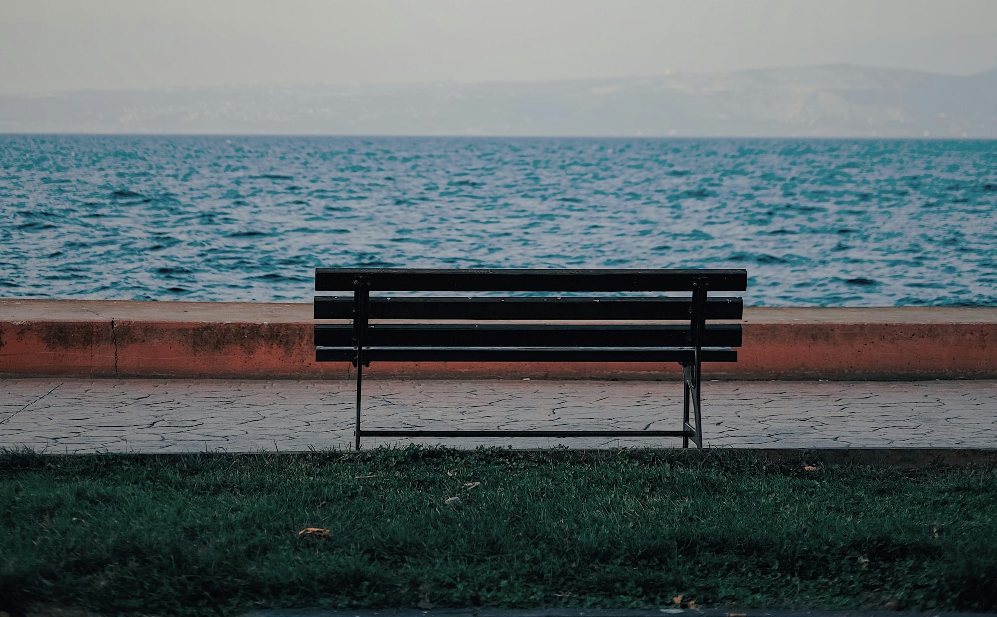 a bench sitting on the side of a road next to the ocean