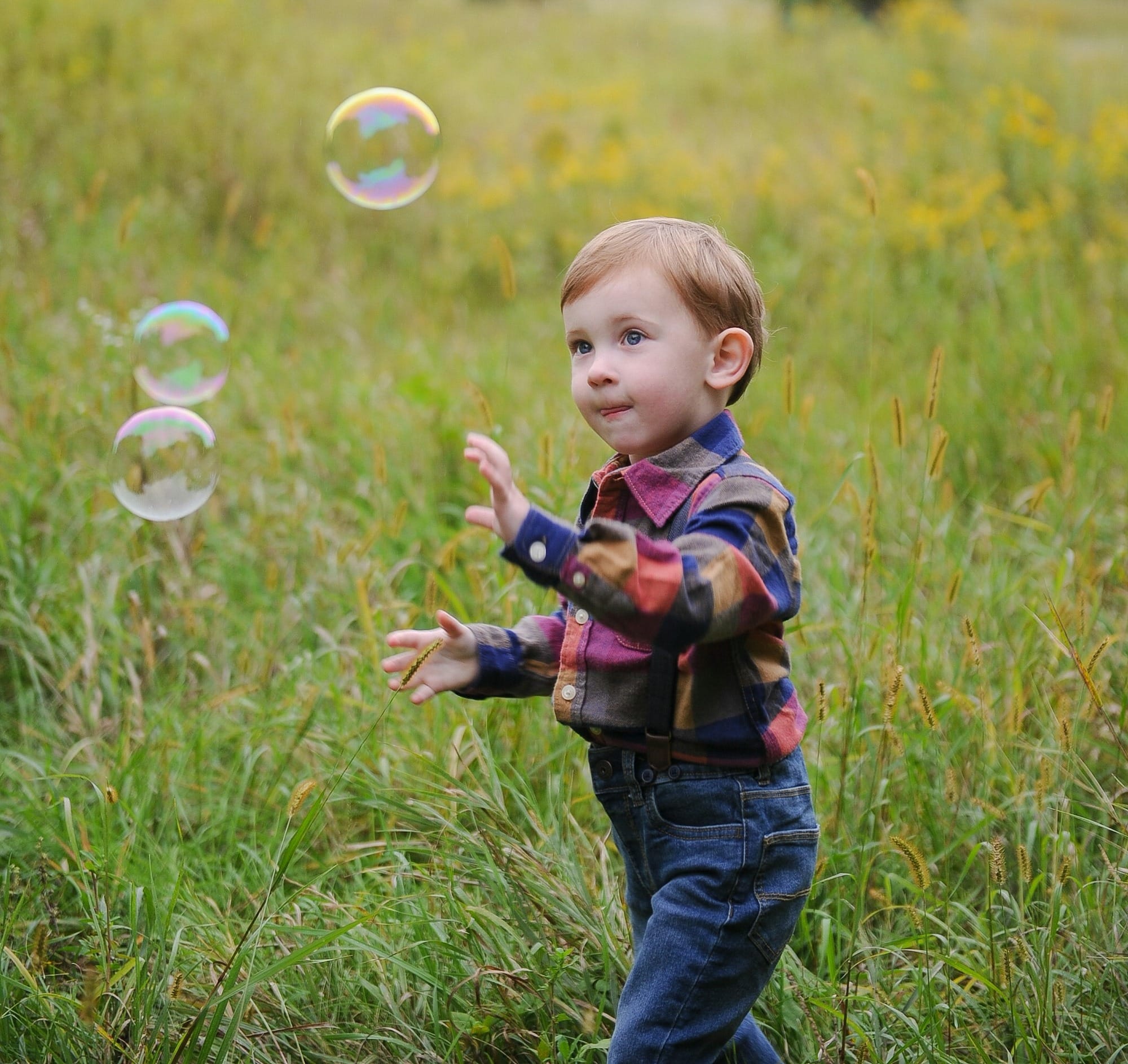 a little boy playing with soap bubbles in a field