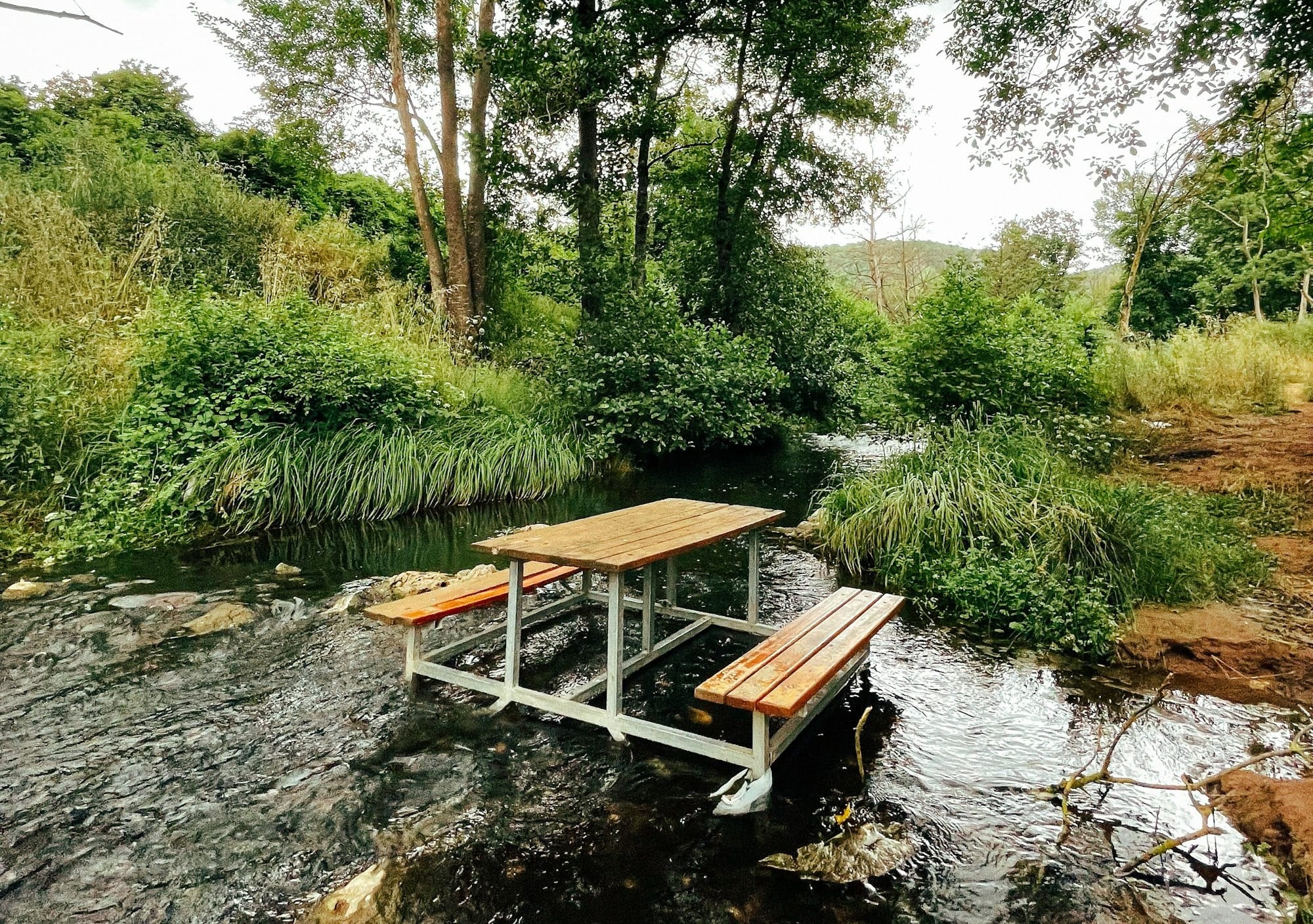 a wooden picnic table sitting on top of a river