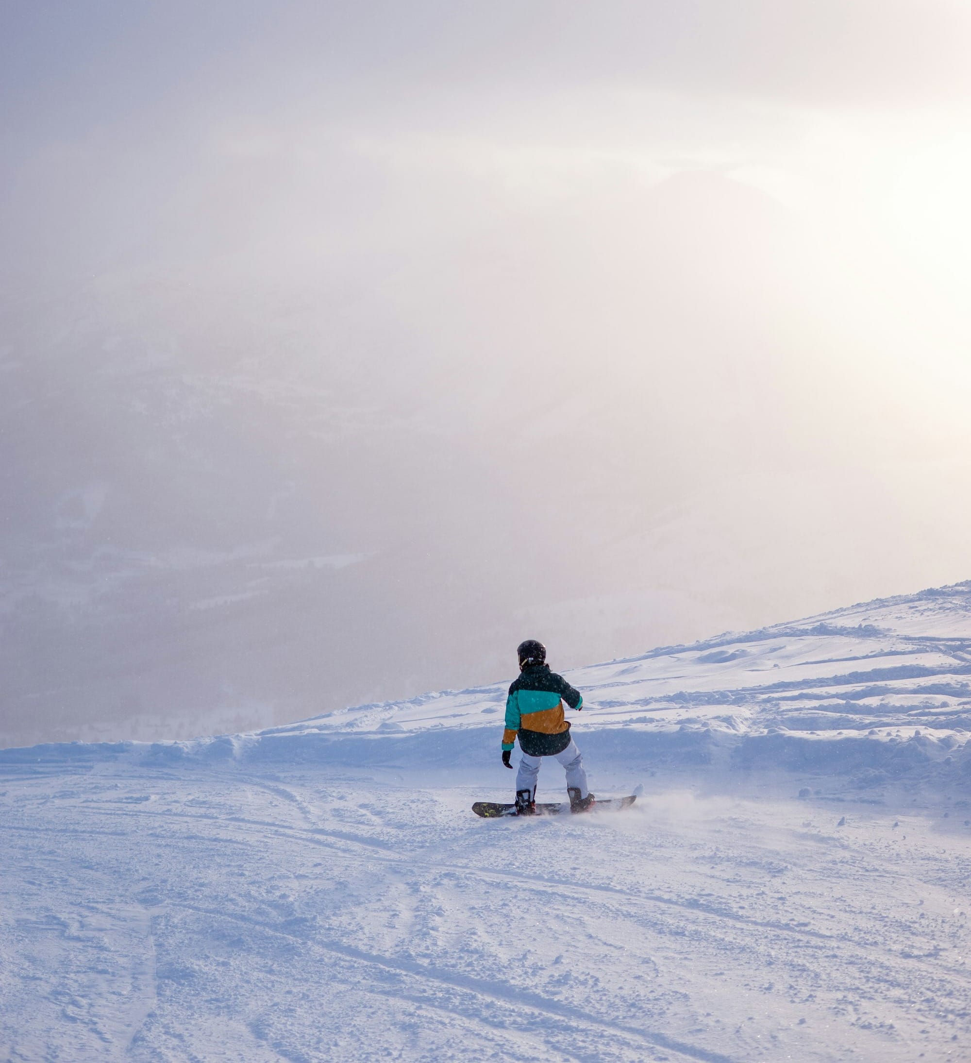 a person riding a snowboard down a snow covered slope